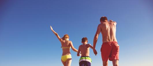 Famiglia felice corre sulla spiaggia al tramonto.